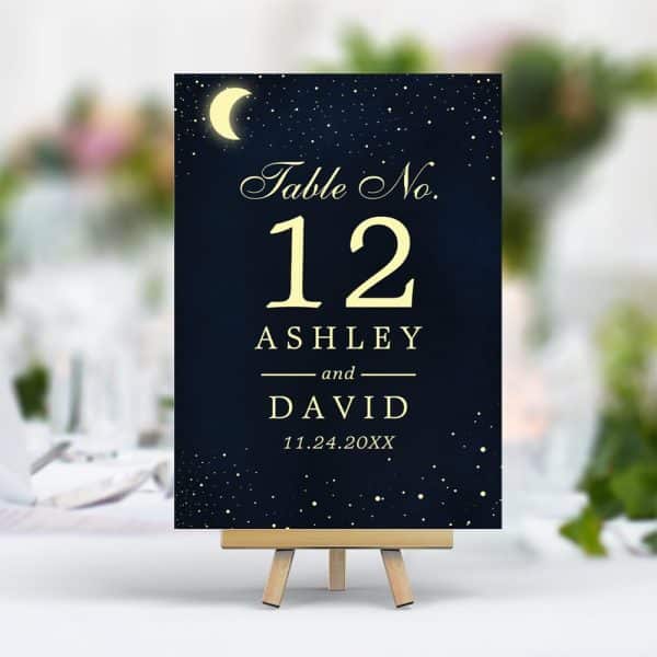 Dark Blue Table Number Card With Gold Lettering; Shows Table 12 For Ashley And David, With A Date And A Crescent Moon.