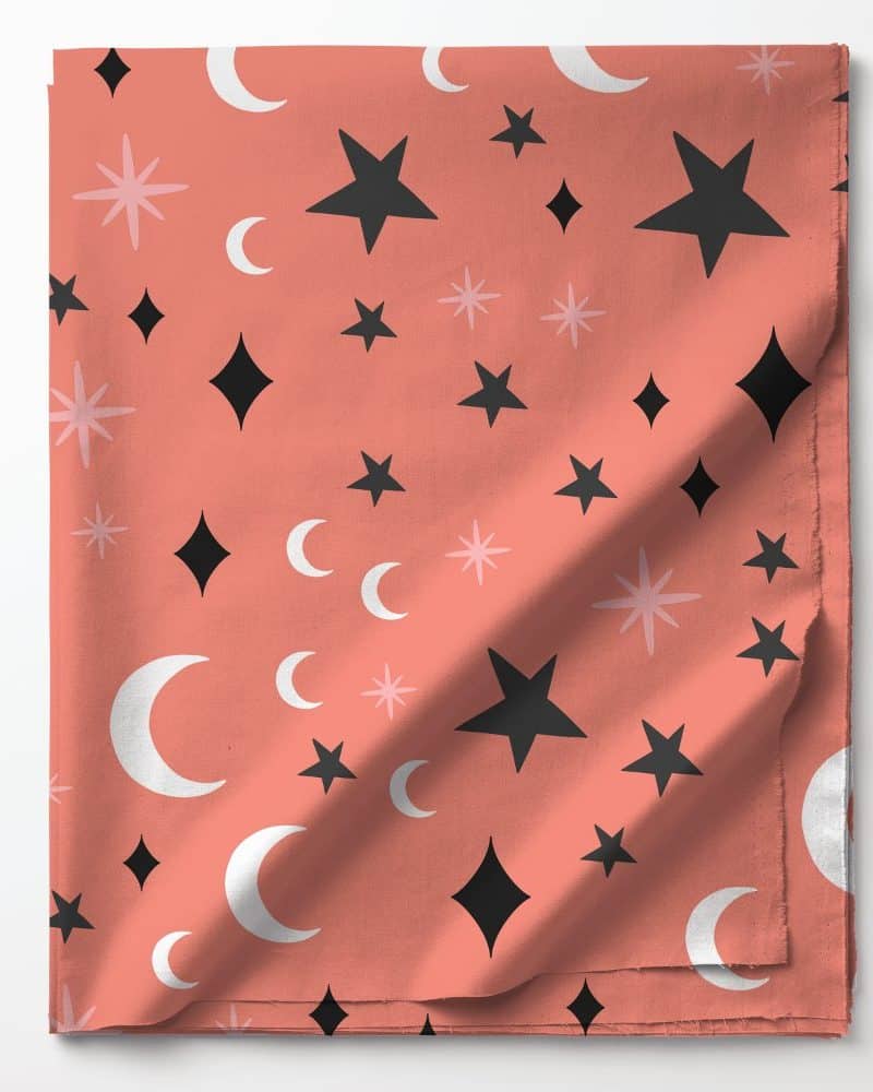 Coral fabric with a repeating pattern of black stars, white crescent moons, and pink starbursts.