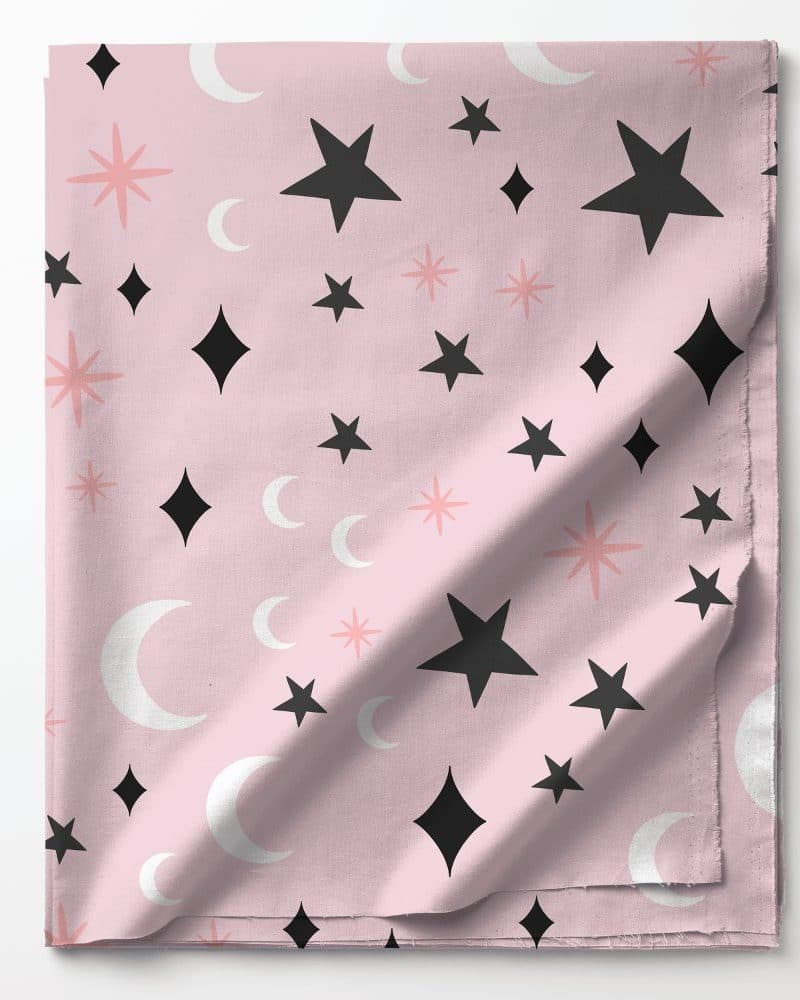 Pink fabric with a repeating pattern of black and white stars, moons, and pink starbursts.