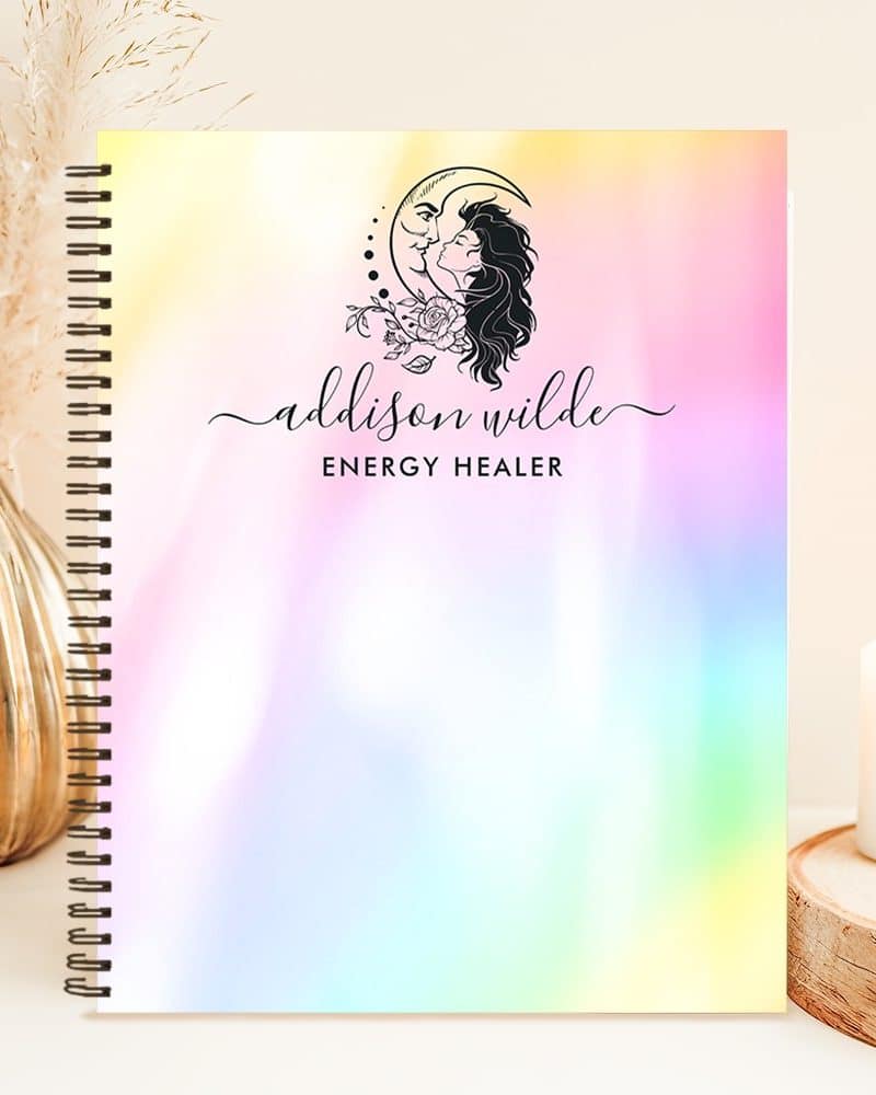 Spiral-bound notebook with a pastel rainbow ombre cover featuring a logo of a woman and a crescent moon. The logo also includes the name Addison Wilde, Energy Healer.