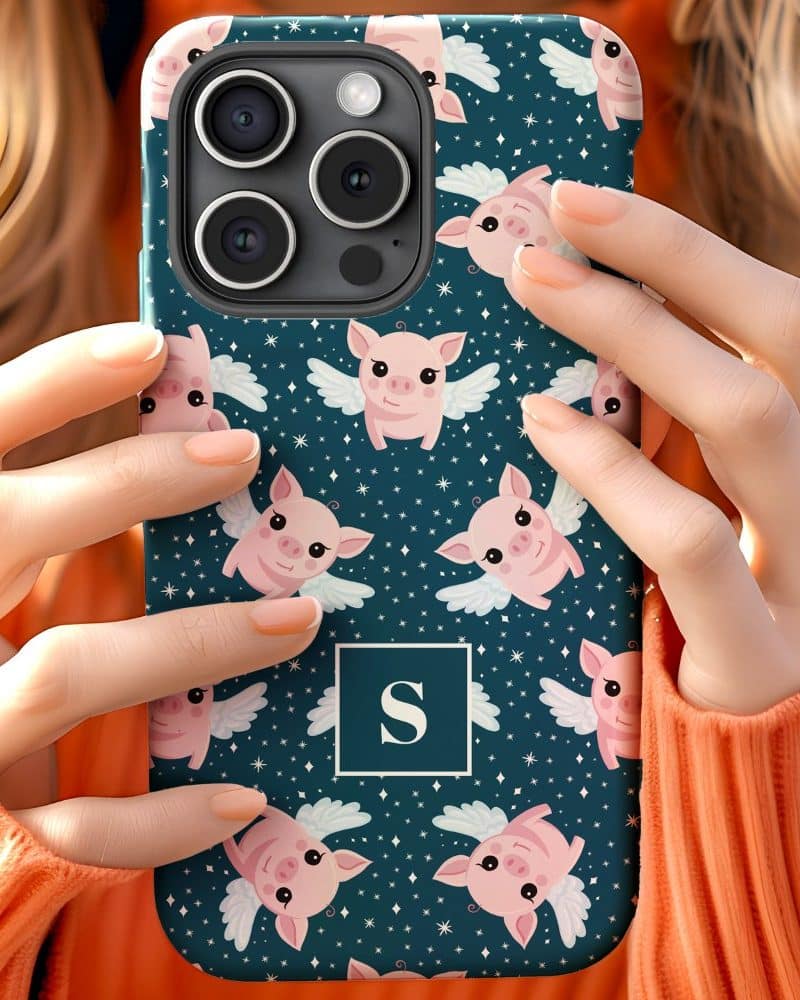 Woman's hands holding a teal phone case featuring a repeating pattern of pink pigs with wings. The case also includes a monogram.