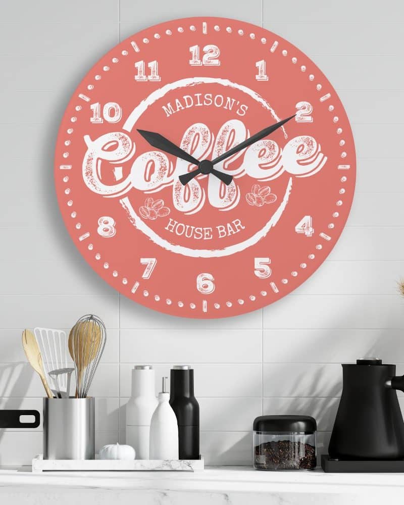 Coral round clock with black hands and white coffee themed design.