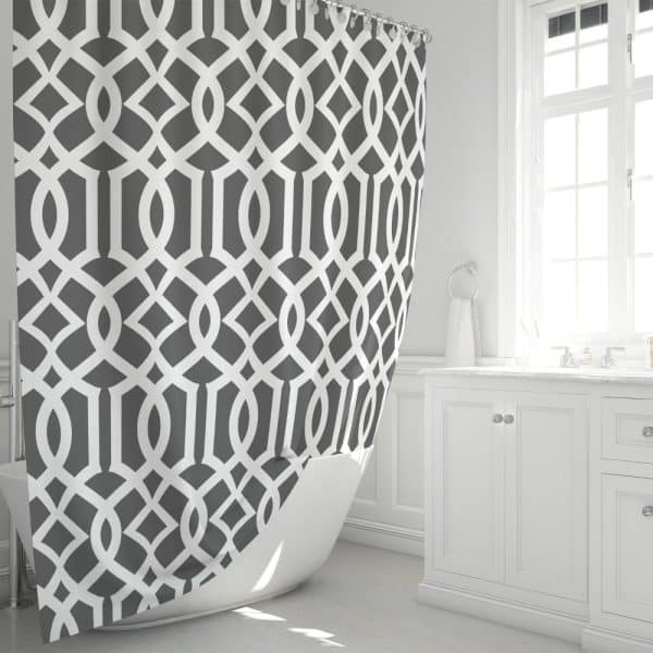 Gray And White Geometric Patterned Shower Curtain Partially Draped Over A White Bathtub.