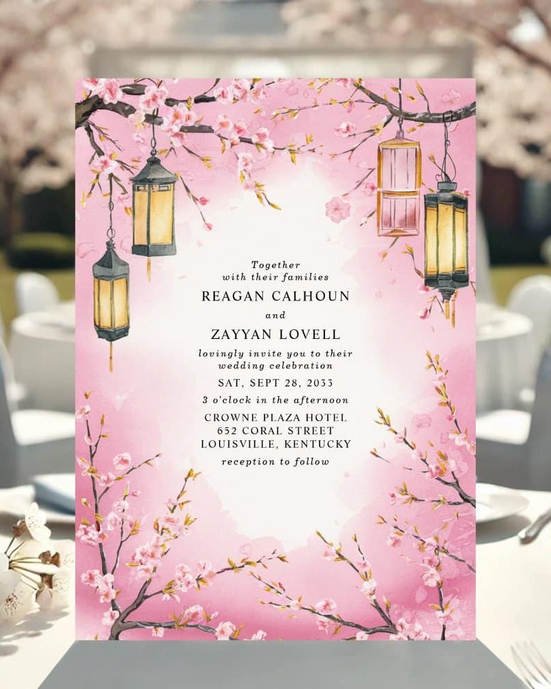 Pink wedding invitation with cherry blossoms and lanterns, announcing the wedding of Reagan Calhoun and Zayyan Lovell.