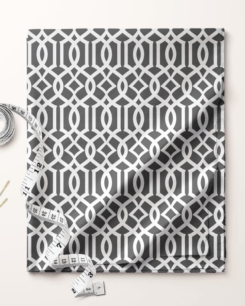 Gray fabric with a white geometric pattern, accompanied by a tape measure and needles.