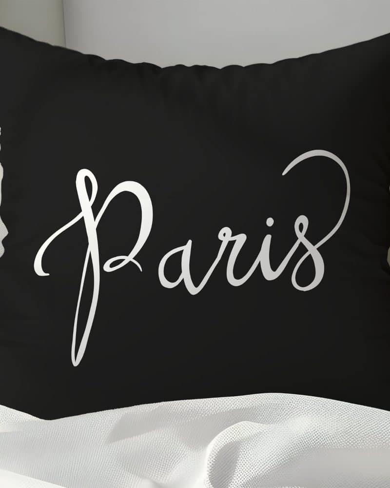 Black pillow with the word Paris in a white script font.