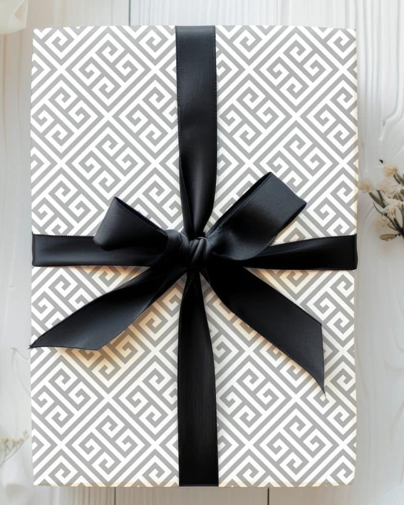 Gift box with gray Greek key pattern wrapping paper and black ribbon.