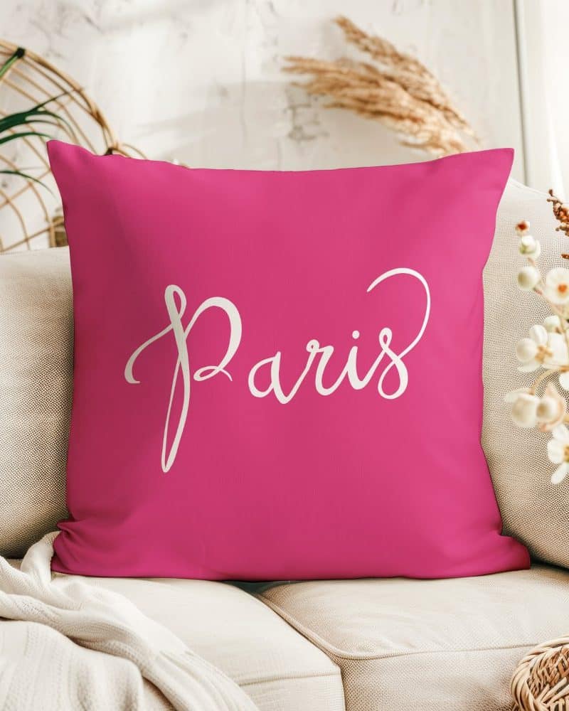 Pink square pillow with the word Paris in white script.