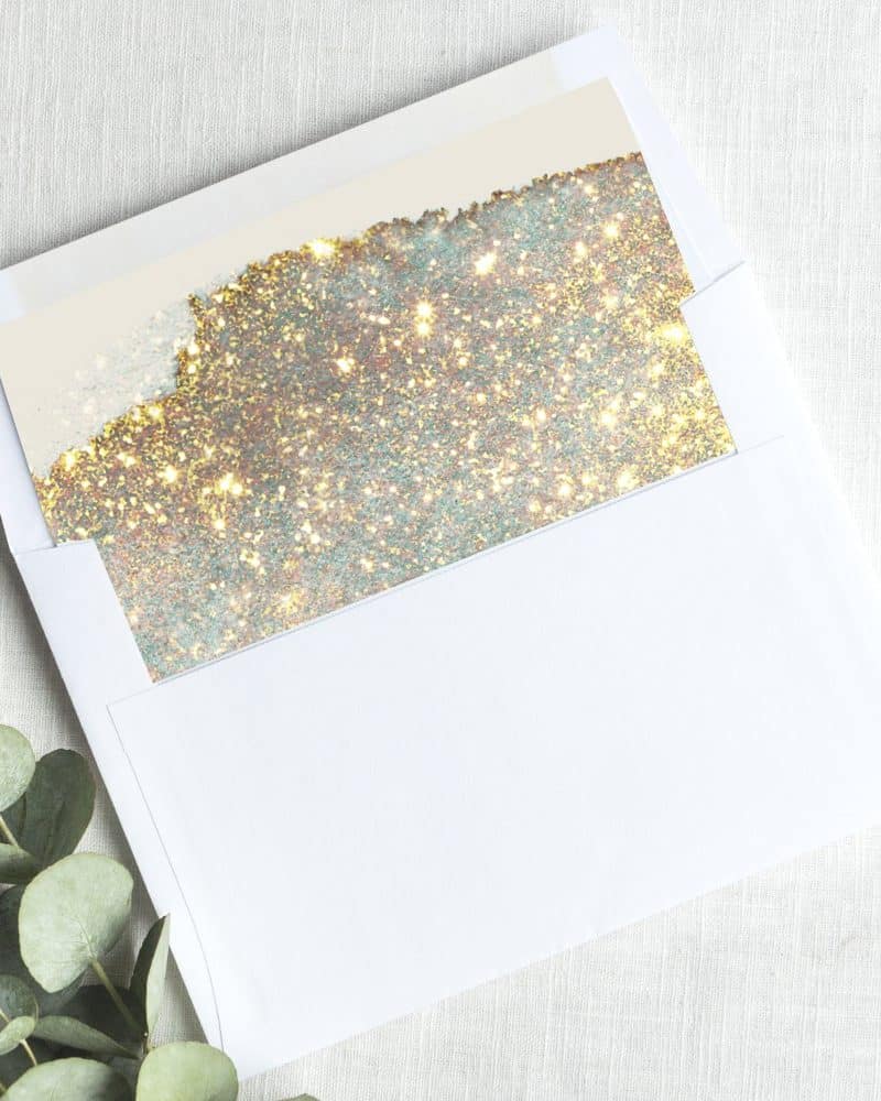 A white envelope containing a gold and silver glitter insert.