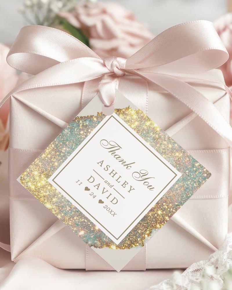 A wedding thank you gift tag with gold glitter design, featuring the names Ashley and David and the date.