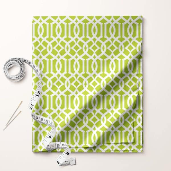 Lime Green Fabric With A White Geometric Pattern, Partially Folded, Next To A Tape Measure And Sewing Needles.