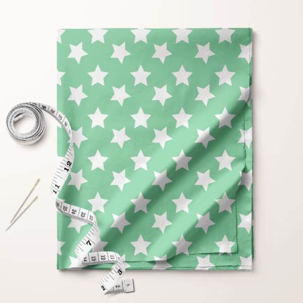 Light Green Fabric With A White Star Pattern, Accompanied By A Tape Measure And Needles.