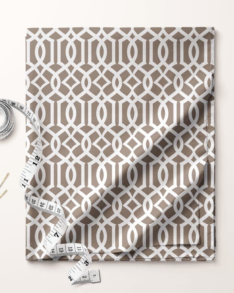 Beige fabric with a white geometric pattern, accompanied by a tape measure and needles.
