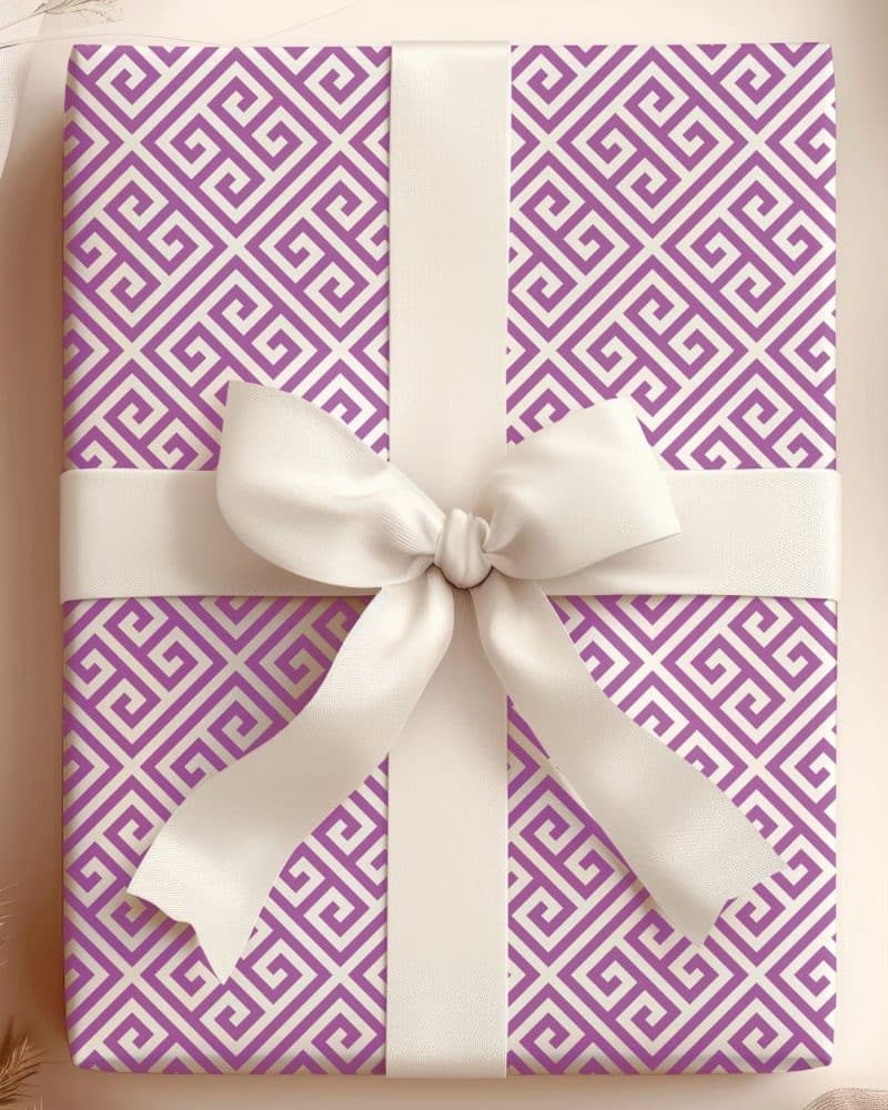 Gift wrapped in purple and cream Greek key patterned paper with a large white bow.