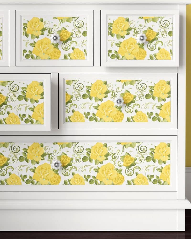 White dresser with yellow rose and green leaf patterned drawer fronts.