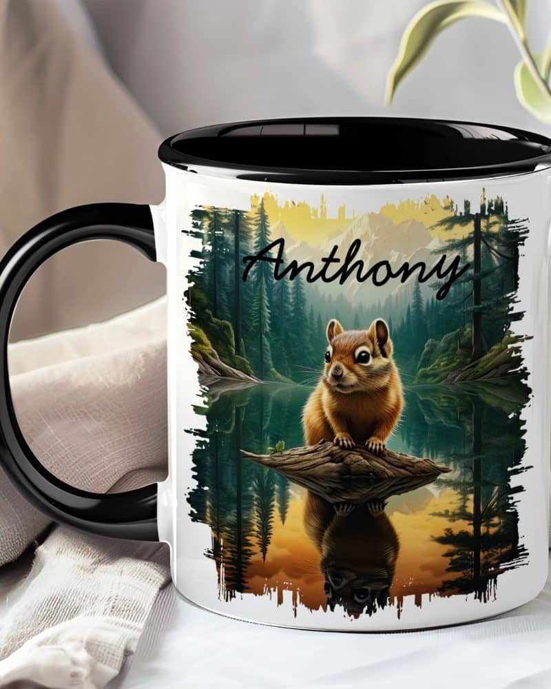 A black-handled mug with a personalized name, Anthony, and a painting of a chipmunk sitting on a log over a lake in a forest.