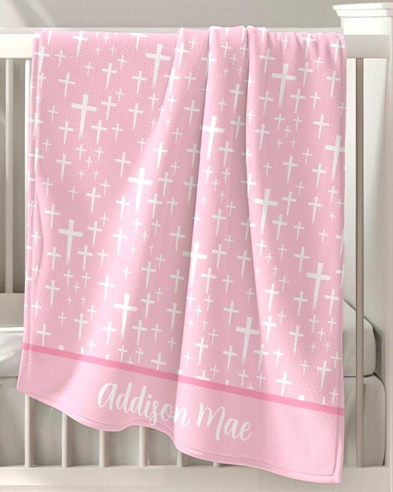 Pink baby blanket with white cross pattern and personalized name.