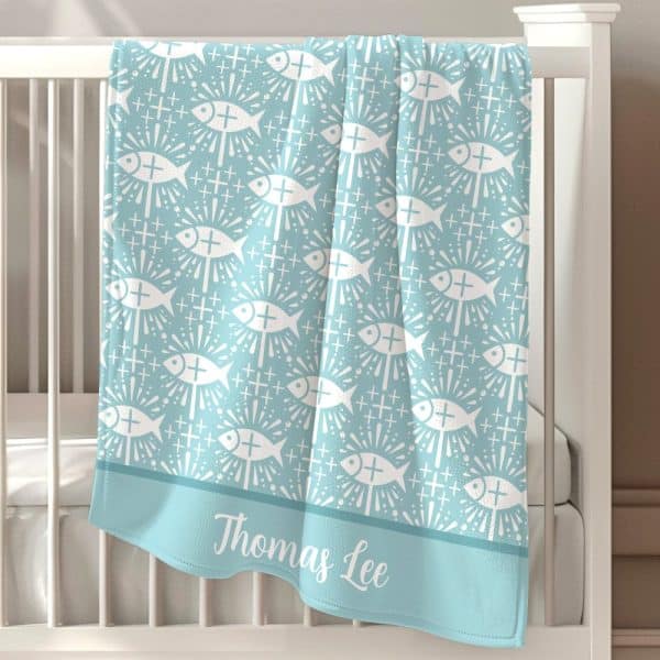 Light Blue Baby Blanket With A Repeating Pattern Of White Stylized Fish And Crosses, Personalized With The Name Thomas Lee.