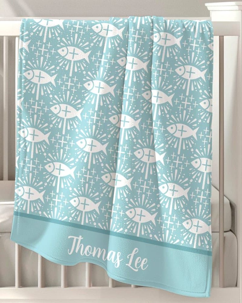 Light blue baby blanket with a repeating pattern of white stylized fish and crosses, personalized with the name Thomas Lee.