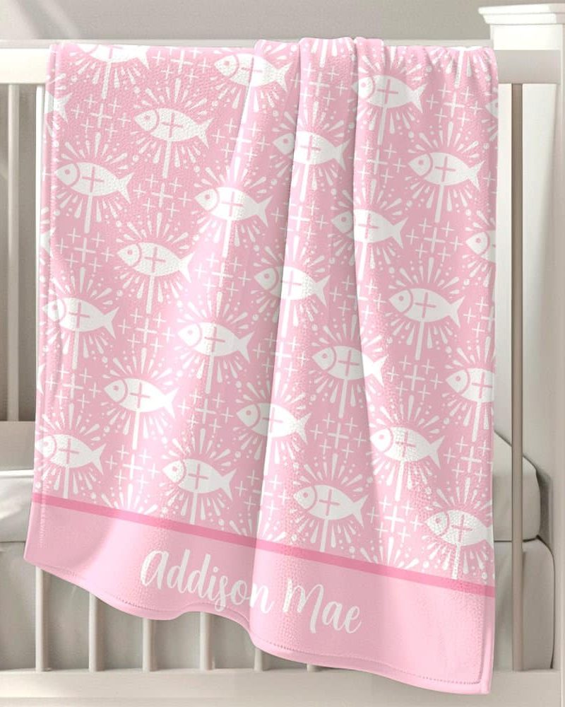 Pink baby blanket with a repeating pattern of white stylized fish and crosses, personalized with the name Addison Mae.