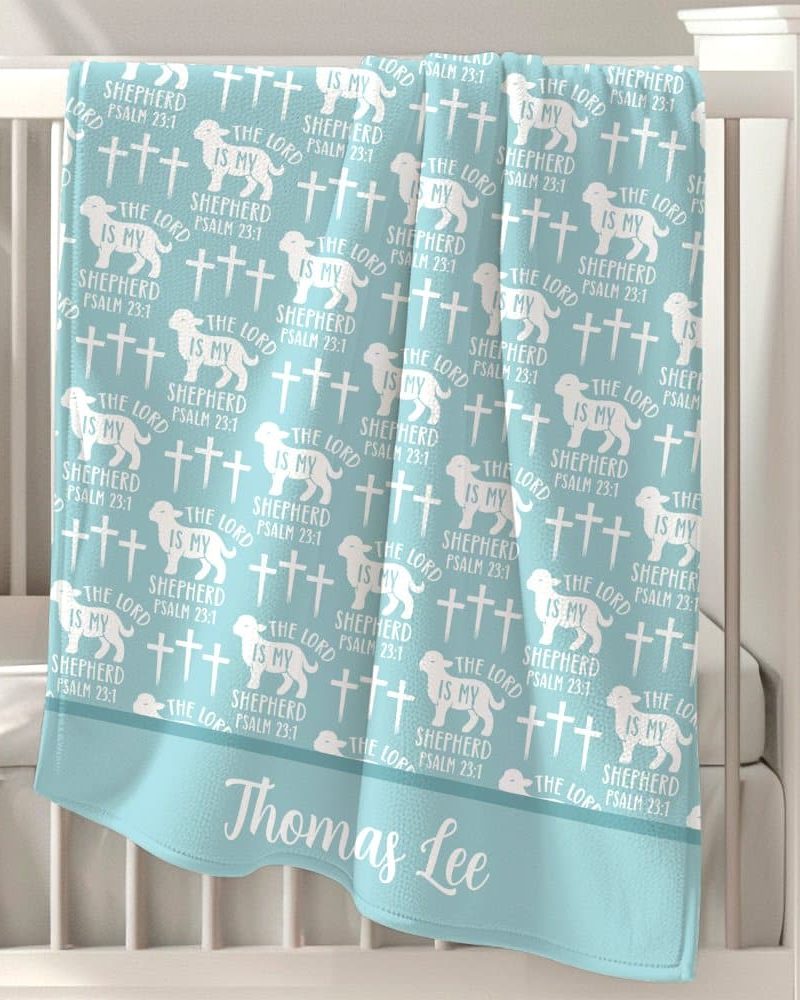 Light blue baby blanket with a repeating pattern of lambs, crosses, and the text "The Lord is my Shepherd, Psalm 23:1," personalized with the name Thomas Lee.