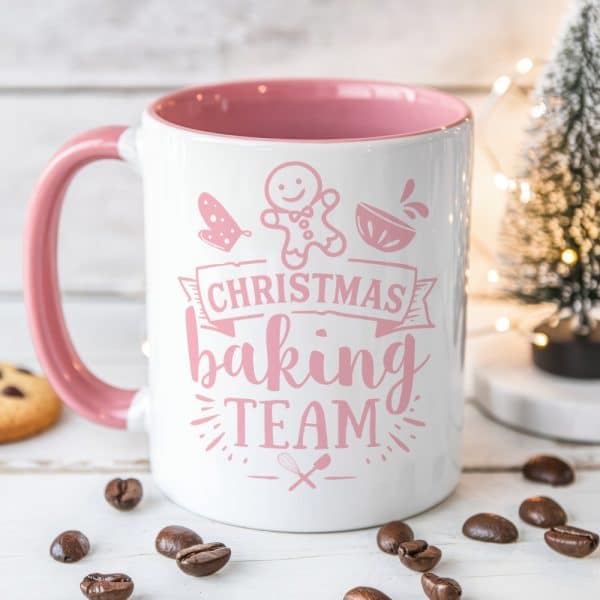 White Mug With Pink Handle And Interior, Displaying Pink Text That Reads Christmas Baking Team Along With Related Illustrations.