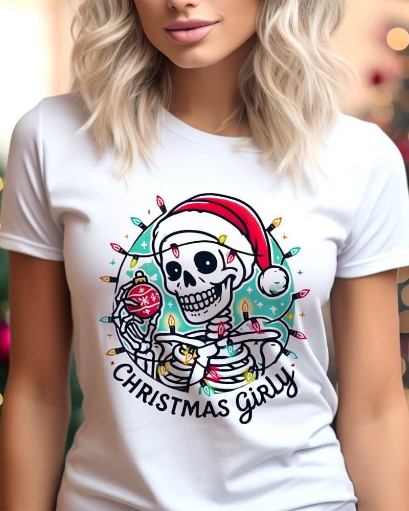 White t-shirt featuring a skeleton wearing a Santa hat and holding an ornament, surrounded by Christmas lights.