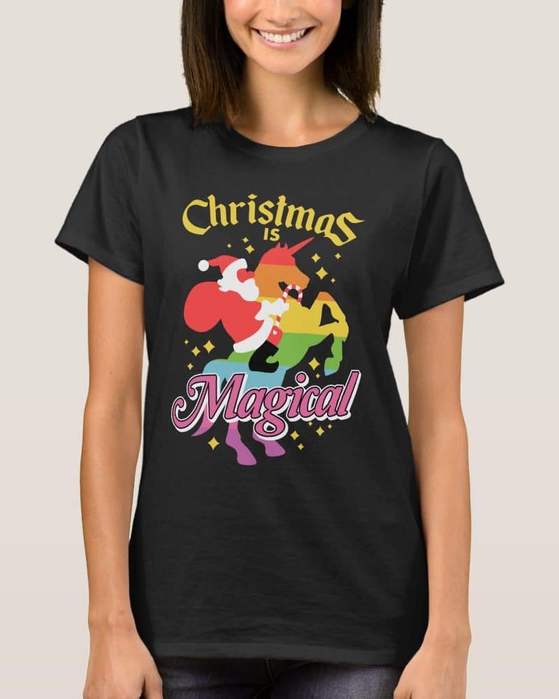 Black t-shirt featuring a rainbow unicorn with Santa Claus riding it, text above reads Christmas is, text below reads Magical.