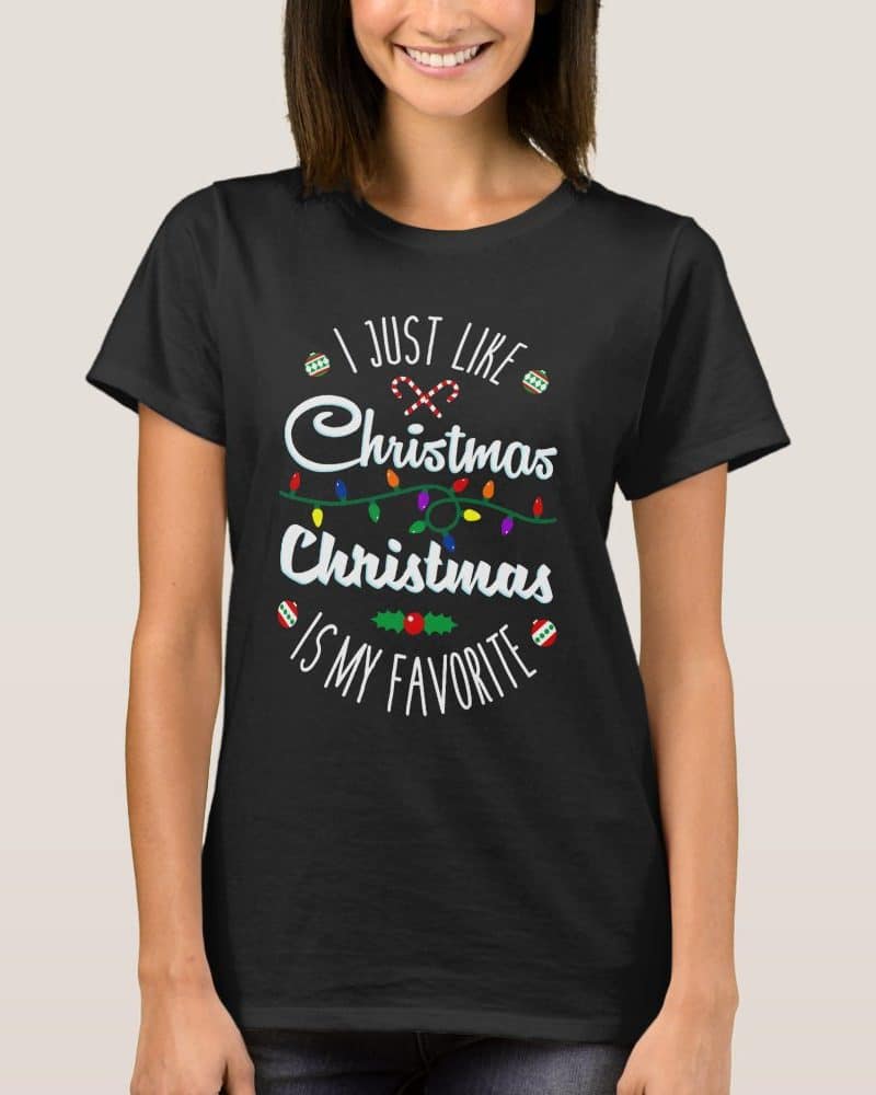 Woman wearing a black t-shirt with a Christmas design that says I just like Christmas Christmas is my favorite.