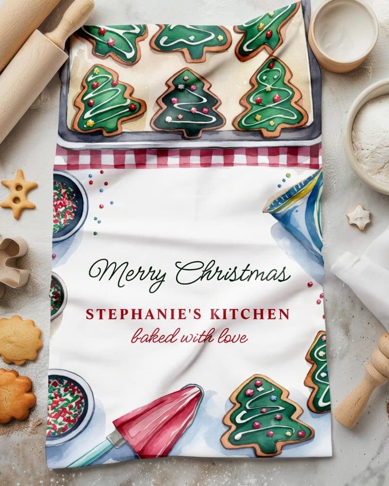 Christmas tea towel with watercolor illustration of Christmas tree cookies and baking supplies; Merry Christmas and Stephanie's Kitchen text.
