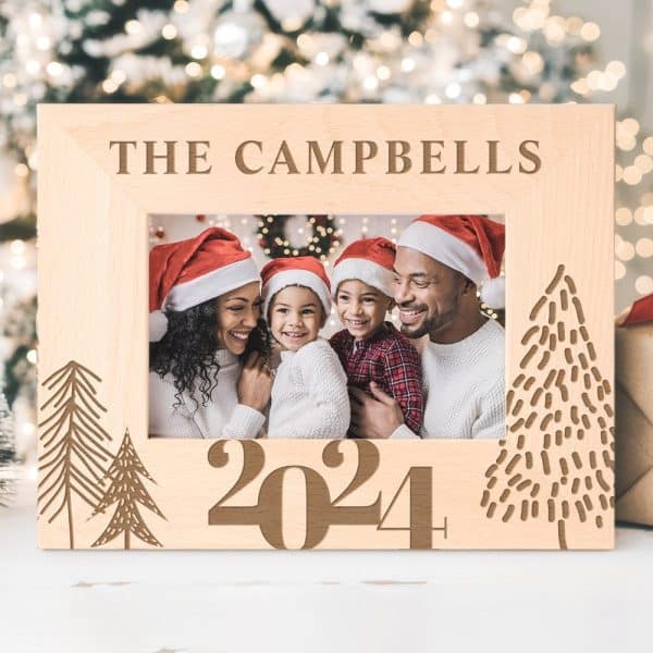 A Light Wood Photo Frame Displays A Family Christmas Photo. The Frame Is Engraved With The Campbell Family Name And The Year 2024, Along With Stylized Christmas Trees.
