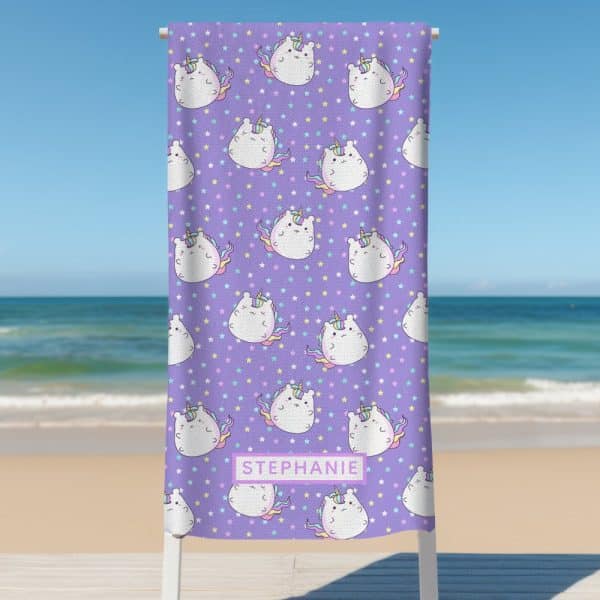 Purple Beach Towel With A Repeating Pattern Of Cartoon Unicorns And Stars; The Name Stephanie Is Printed On The Towel.