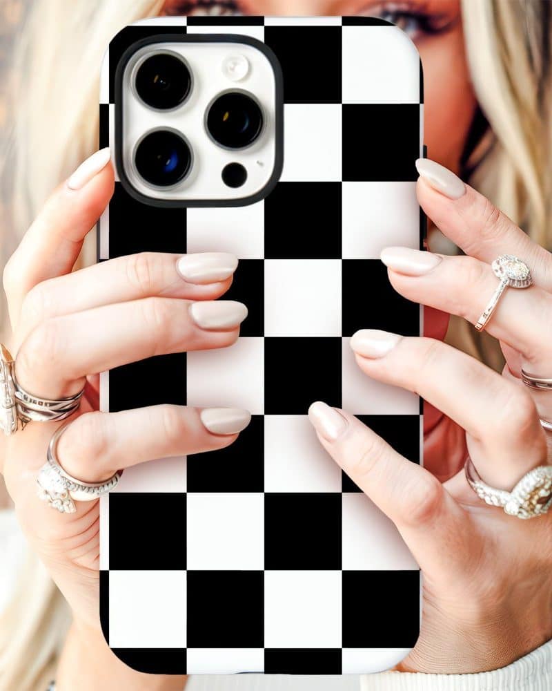 Woman's hands holding an iPhone in a black and white checkered phone case.