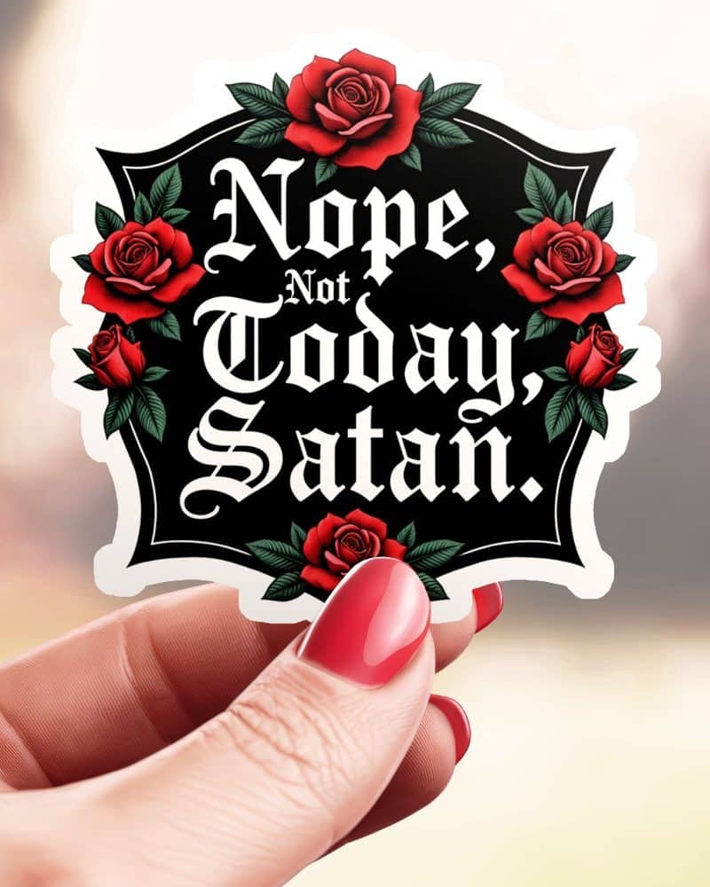 Hand holding a sticker that says Nope, Not Today, Satan in a gothic style font, surrounded by red roses.