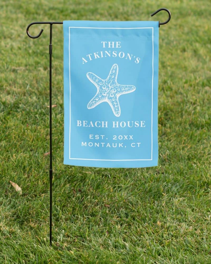 Light blue beach house garden flag with a starfish and the Atkinson family name.