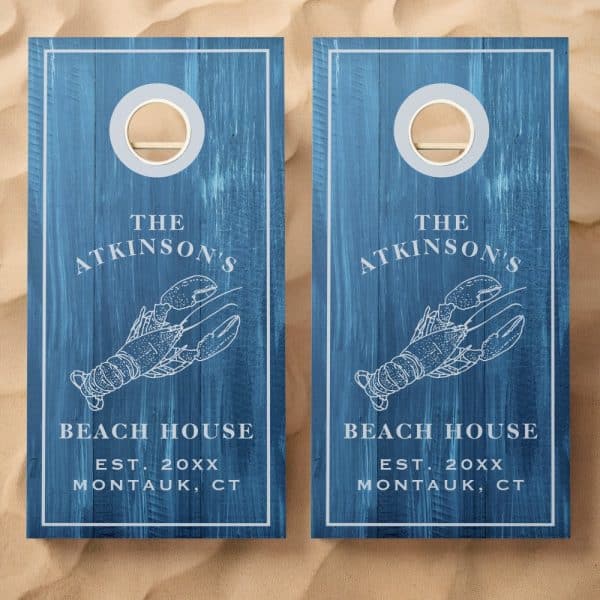 Two Blue Cornhole Boards With A Lobster Design, The Atkinsons Beach House, And Establishment Year.