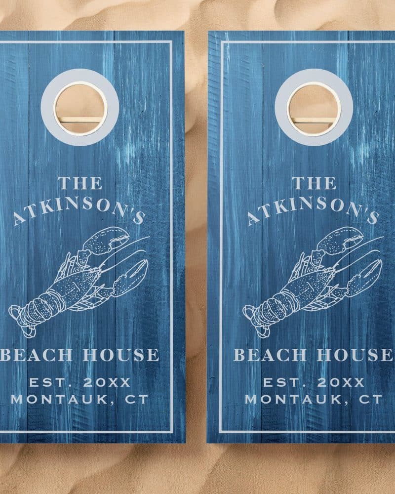 Two blue cornhole boards with a lobster design, The Atkinsons Beach House, and establishment year.