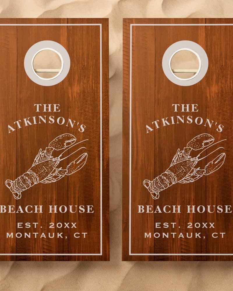 Pair of wooden cornhole boards, each featuring a lobster illustration and The Atkinsons Beach House text.