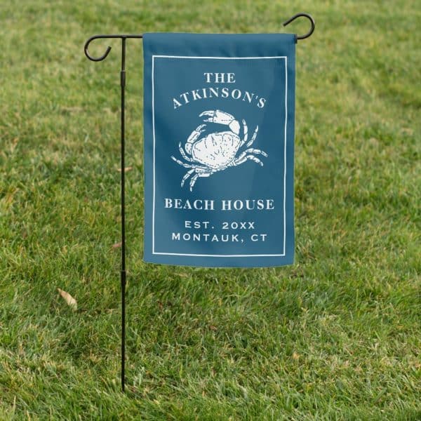 A Dark Blue Garden Flag With A White Crab Illustration, Text Reading The Atkinsons Beach House Est. 20Xx Montauk, Ct.