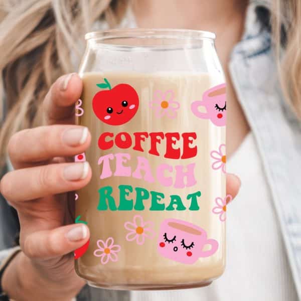 Person Holding A Glass With Coffee And The Words Coffee Teach Repeat. The Glass Is Decorated With Cartoon Apples And Coffee Cups.