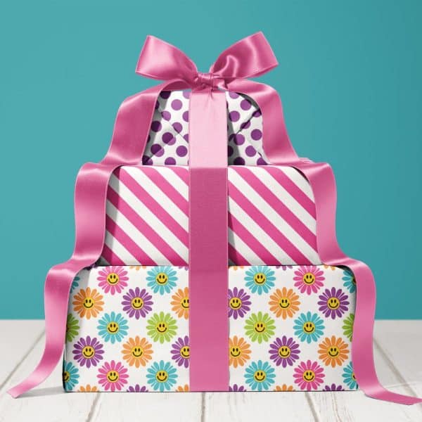 Stack Of Three Gifts Wrapped In Colorful Paper With A Large Pink Ribbon.