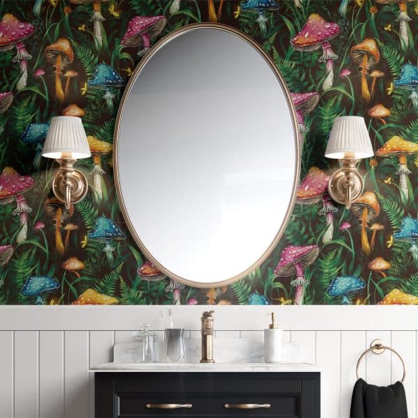 Oval Mirror With Brass Frame Above A Bathroom Vanity, Set Against A Wall With Dark Green Wallpaper Featuring Colorful Mushrooms And Ferns.