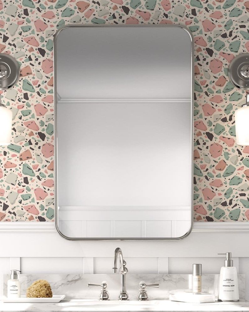 Bathroom vanity with a terrazzo patterned wall and a rectangular mirror.