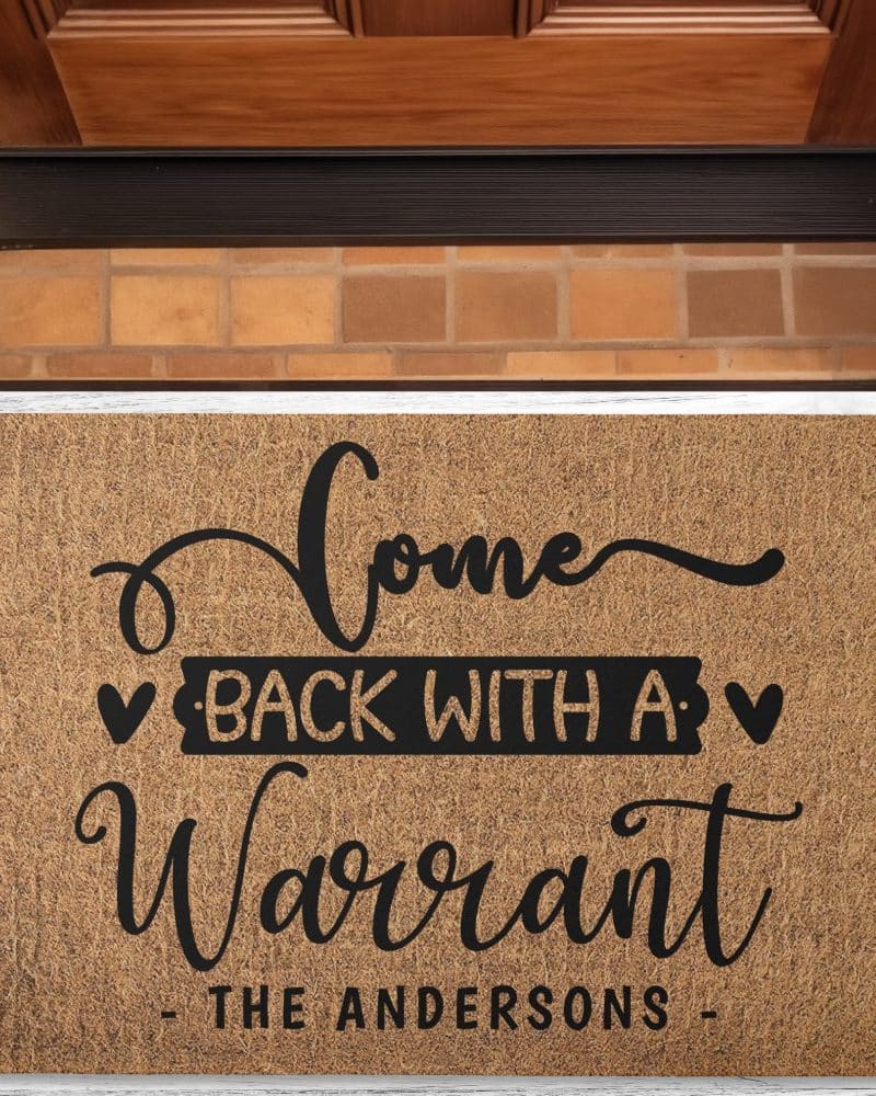 Brown coir doormat with the text Come Back With A Warrant, The Andersons.