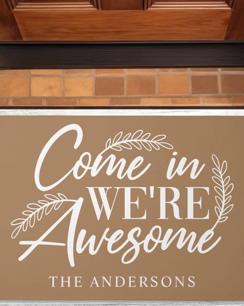 Tan welcome mat with the text Come in We're Awesome and the name The Andersons.