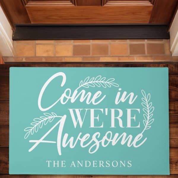 Teal Welcome Mat With White Lettering That Says Come In We'Re Awesome, And The Andersons At The Bottom.
