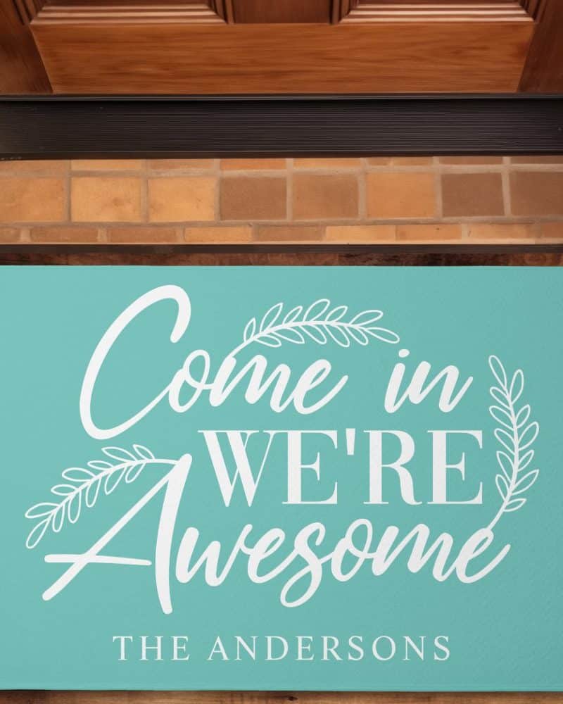 Teal welcome mat with white lettering that says Come in We're Awesome, and The Andersons at the bottom.