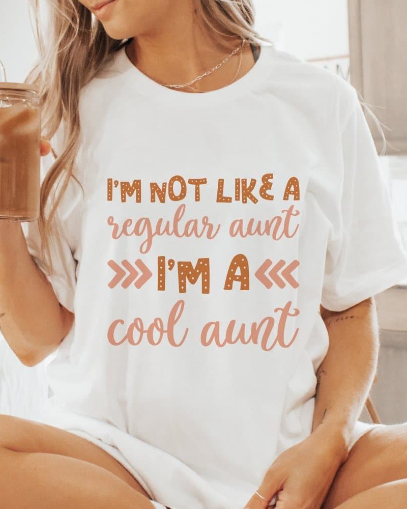 Woman wearing a white t-shirt that says Im not like a regular aunt Im a cool aunt.