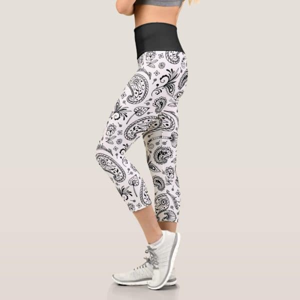 A Woman'S Leg Wearing White Capri Leggings With A Black Paisley Pattern.
