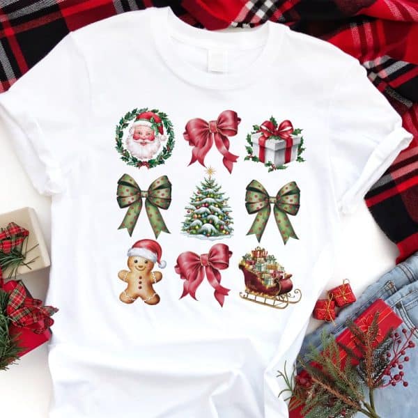 White T-Shirt With A Repeated Pattern Of Festive Christmas Images Including Bows, Santa, A Christmas Tree, A Gingerbread Man, And A Sleigh.